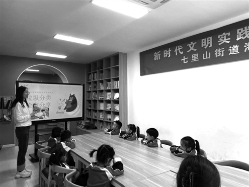 社区工作人员与孩子们一起阅读垃圾分类绘本故事